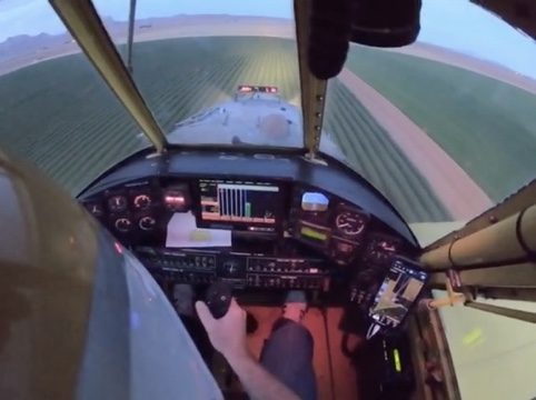 Cockpit view on a spray pass down a green field